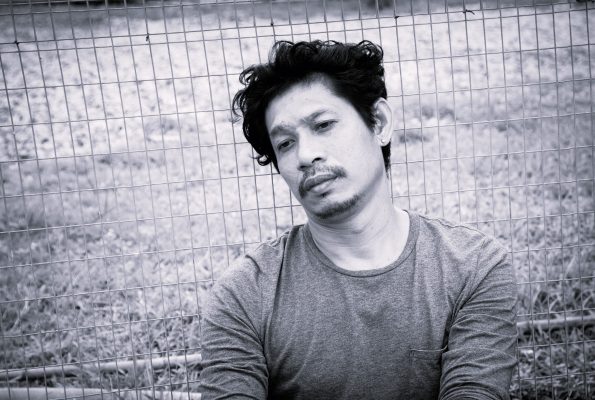 Man sitting in front of fence