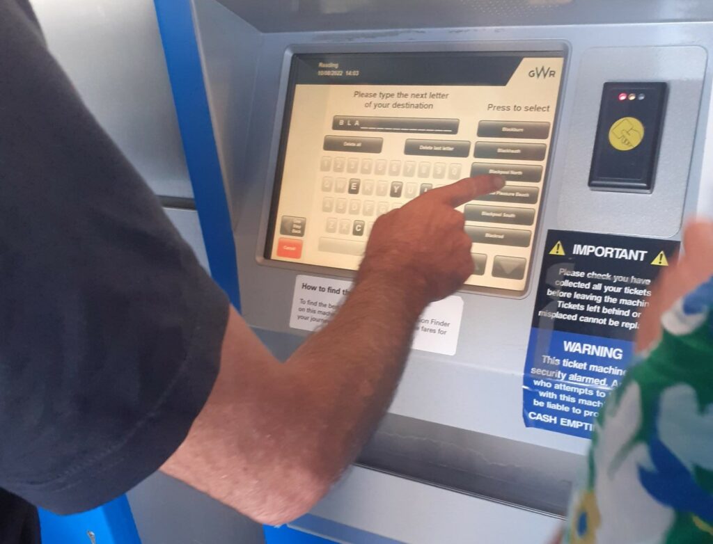 Hand on screen buying a train ticket