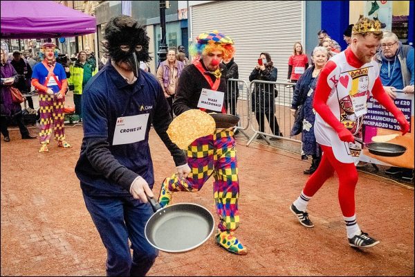 Men dressed as a crow, a clown and a king racing against each other in the Launchpad Pancake Race