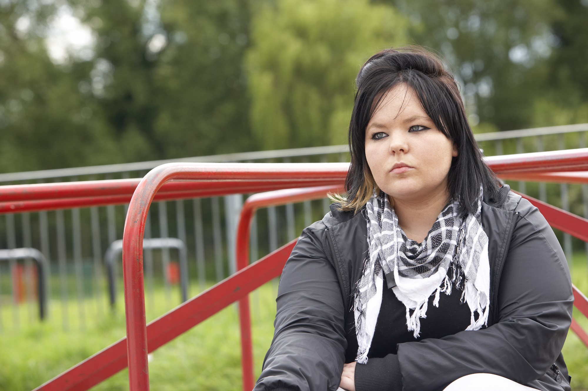 Sad woman sat on roundabout in park