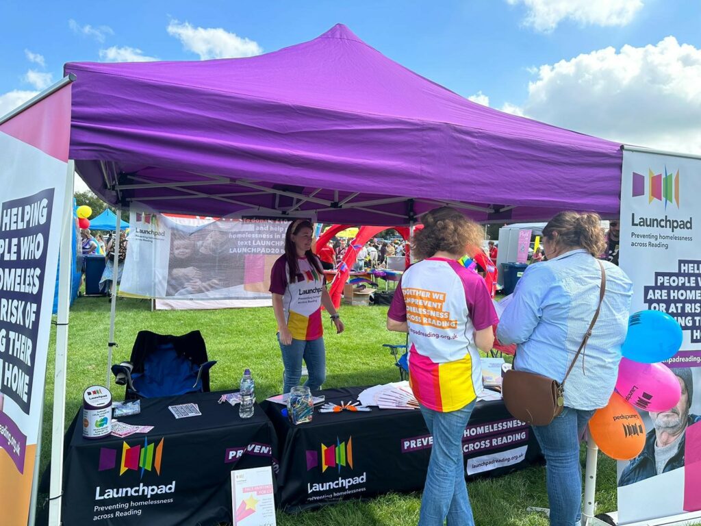 photo of people at a stall at reading Pride looking at leaflets
