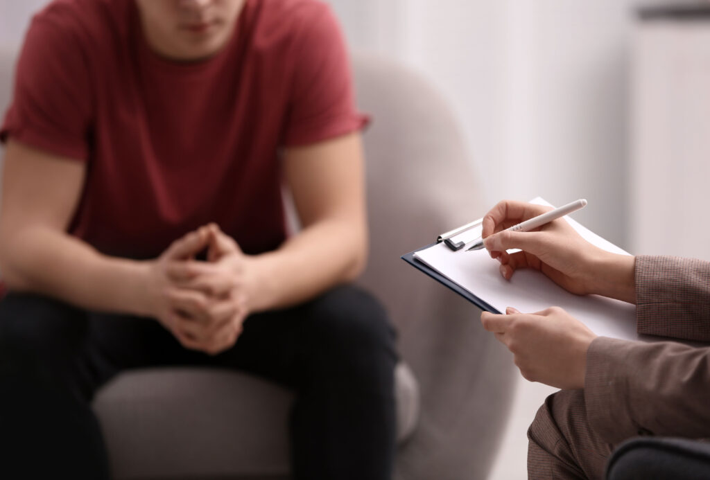 Man getting counselling. hand on a pen on clipboard