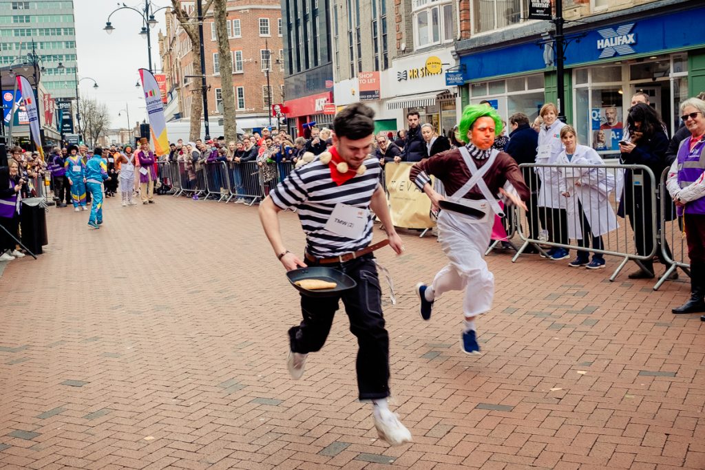 Photo from Launchpad's 2023 Pancake Race - two men in fancy dress running.