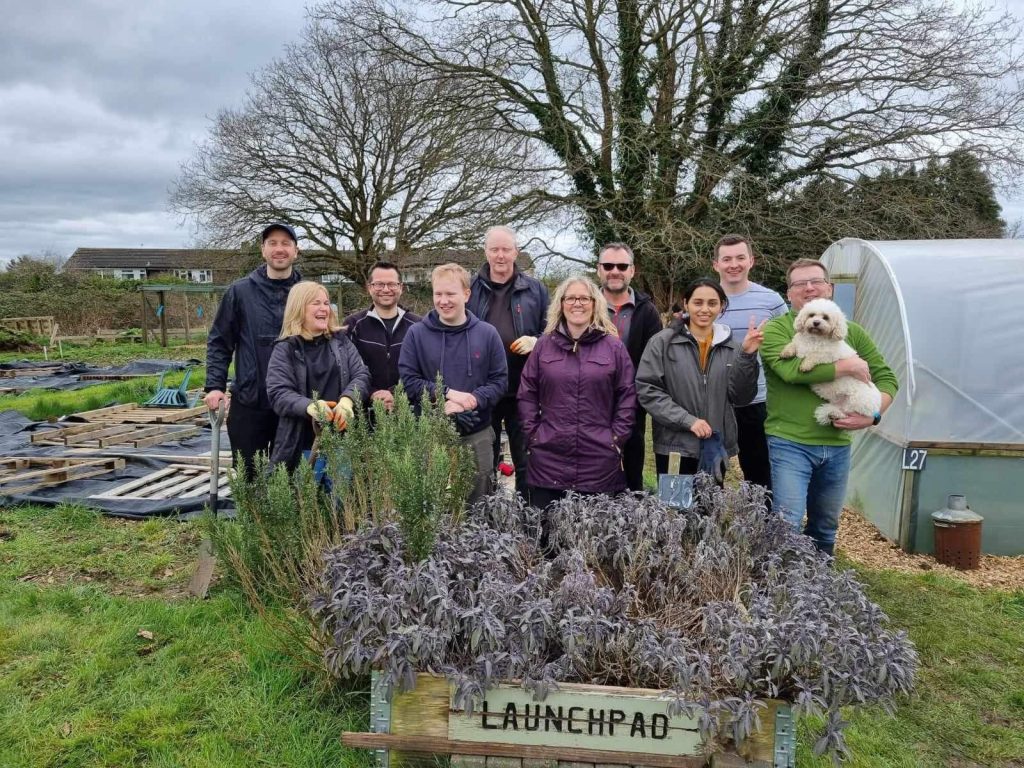 A group of people standing behind the herb bed on the Launchpad allotment