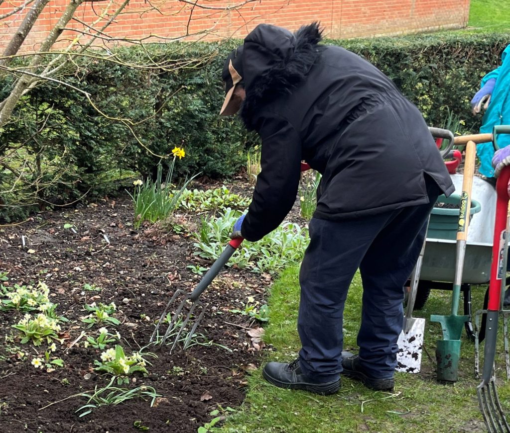 a client from Launchpad 135 gardening with a fork