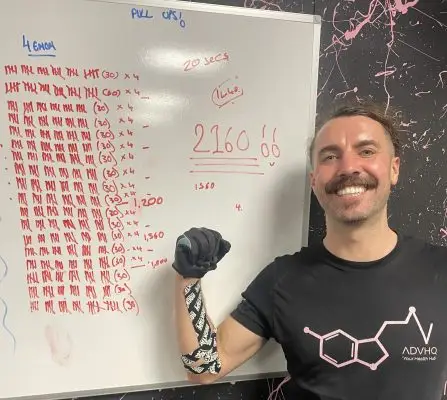 Harvey after completing his pull up challenge for Launchpad, he's smiling and standing in front of a board that's got his pull ups counted on.