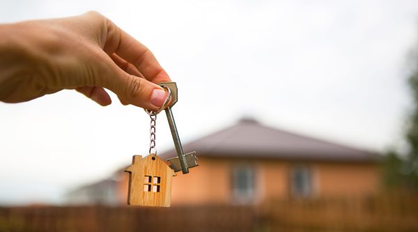 close up hand holding keys with house in background used to illustrate renters rights story