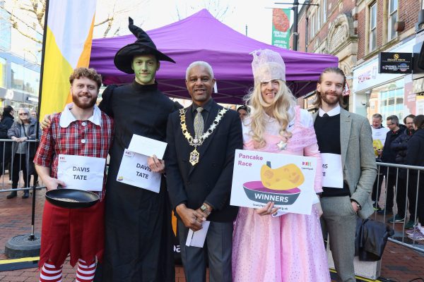 Photos from Launchpad's 2025 Pancake Race, there are people in fancy dress racing, with crowds watching in the background.