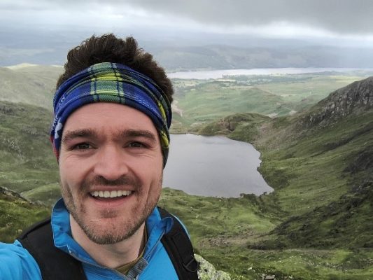 Man with headband looking at the camera with lake behind him