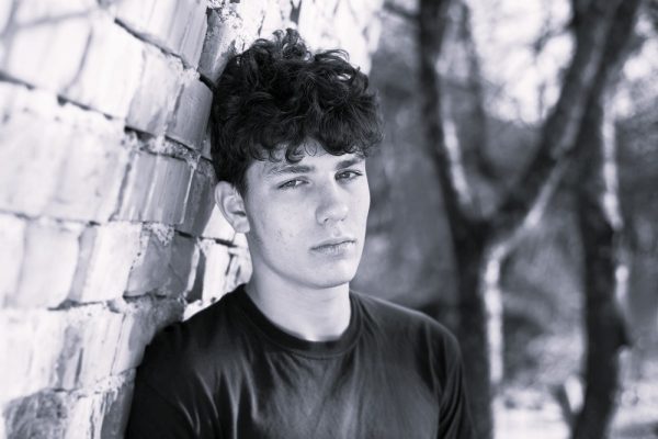 Young man standing next to a wall looking ahead