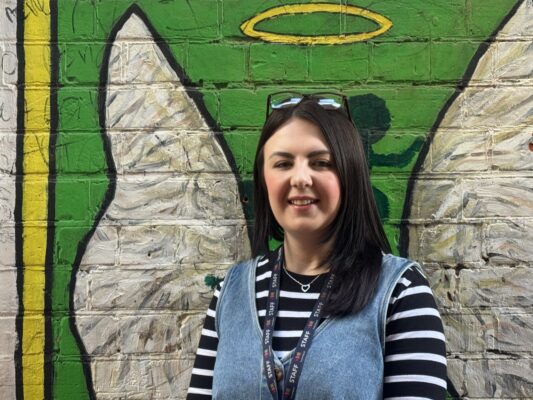Woman in blue dress standing in front of angel wings