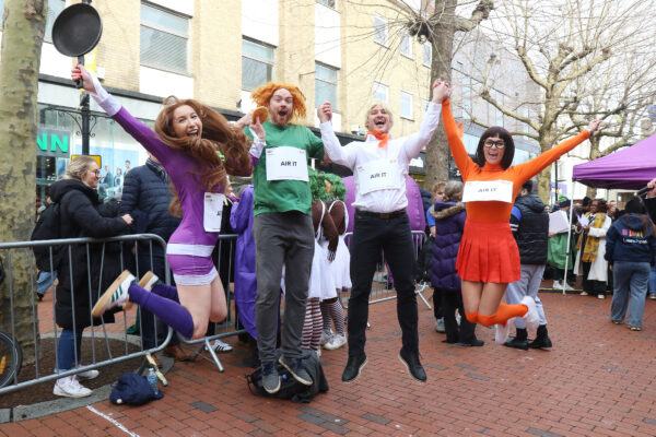 Winners of the 2026 Pancake Race - AirIT - dressed as Scooby Doo characters take a winning leap.