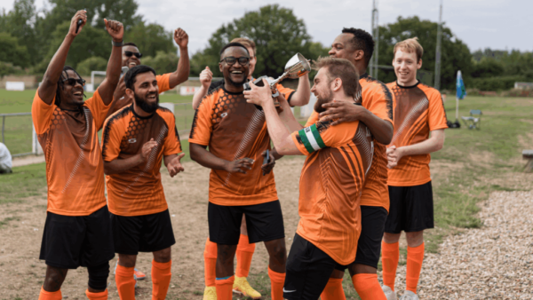 group of men in orange football shirts celebrate with trophy